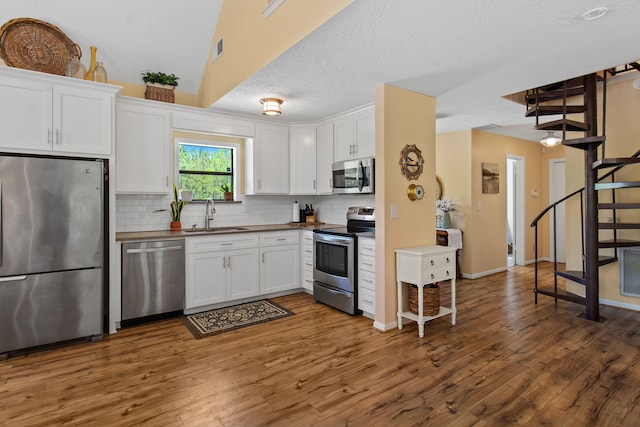 kitchen with white cabinetry, sink, dark wood-type flooring, decorative backsplash, and appliances with stainless steel finishes