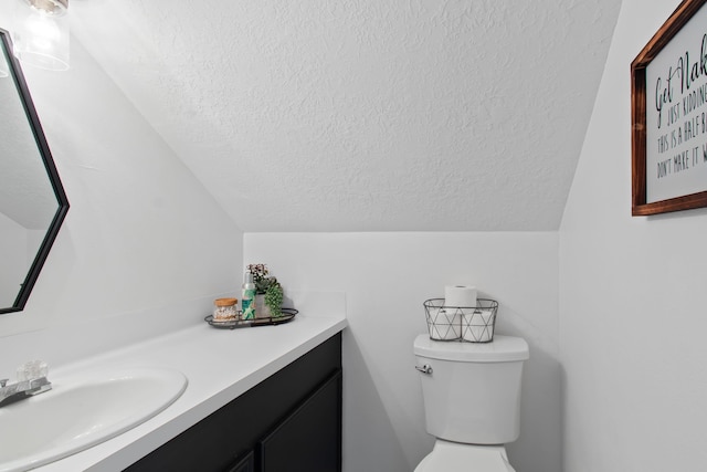 bathroom with vanity, a textured ceiling, toilet, and lofted ceiling