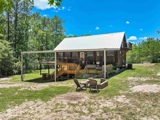 back of property featuring a wooden deck, a sunroom, a yard, and central AC