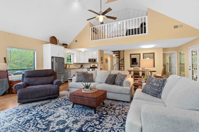 living room featuring wood-type flooring, high vaulted ceiling, and ceiling fan