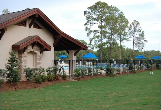 view of property's community with fence, a yard, and a swimming pool