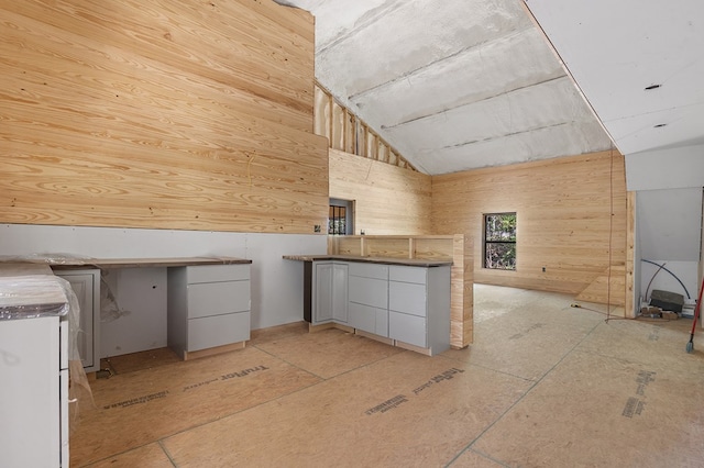 415 Sloe Ln, Brookeland, TX 75931 - kitchen with vaulted ceiling, a peninsula, wood walls, and white cabinets