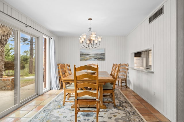 dining space with wooden walls and an inviting chandelier