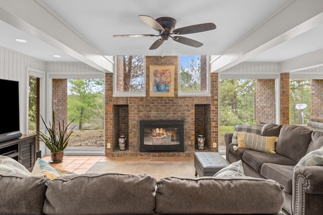 tiled living room featuring a fireplace, ceiling fan, and plenty of natural light