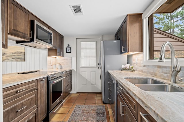 kitchen featuring backsplash, a wealth of natural light, sink, and appliances with stainless steel finishes