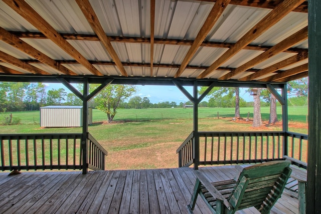 wooden terrace with a lawn, a rural view, and a shed