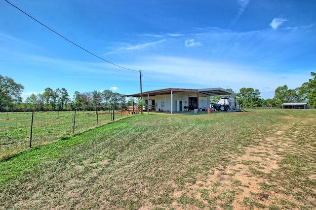 view of yard with an outbuilding, a rural view, and a carport