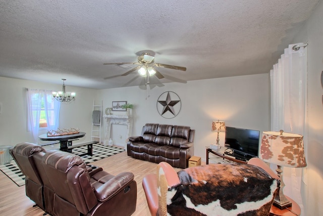 living room with ceiling fan with notable chandelier, light hardwood / wood-style floors, and a textured ceiling