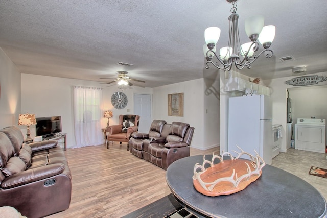 living room featuring a textured ceiling, ceiling fan with notable chandelier, hardwood / wood-style flooring, and washer and clothes dryer