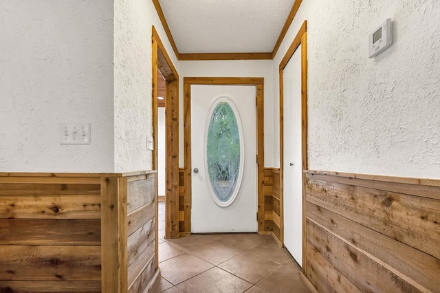 doorway to outside with crown molding, tile patterned floors, and a textured ceiling