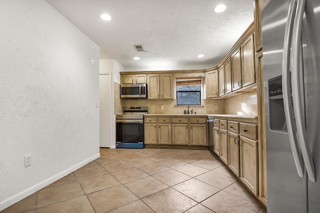 kitchen featuring sink, light tile patterned flooring, a textured ceiling, and appliances with stainless steel finishes