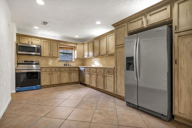 kitchen with tasteful backsplash, appliances with stainless steel finishes, sink, and light tile patterned floors