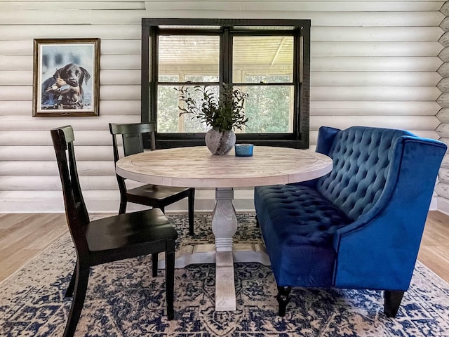 dining area with hardwood / wood-style flooring and log walls