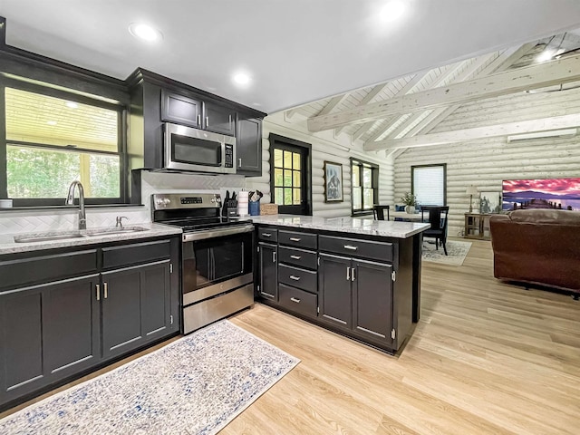 kitchen with wood walls, sink, light hardwood / wood-style flooring, kitchen peninsula, and stainless steel appliances