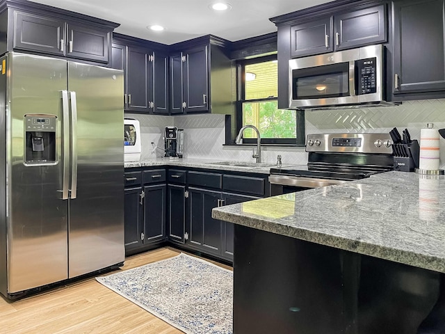 kitchen featuring sink, stainless steel appliances, stone countertops, and light hardwood / wood-style floors