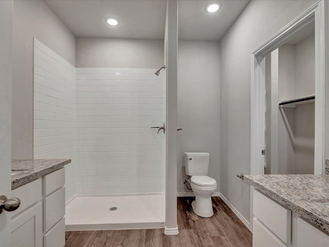 bathroom with a tile shower, wood finished floors, and vanity