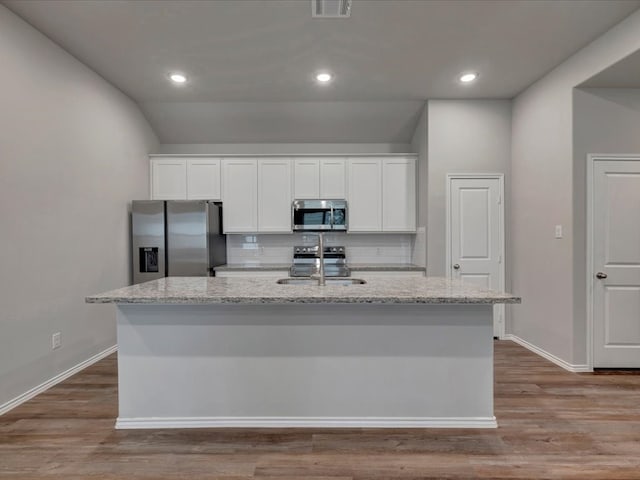 kitchen with light stone counters, appliances with stainless steel finishes, visible vents, and white cabinets