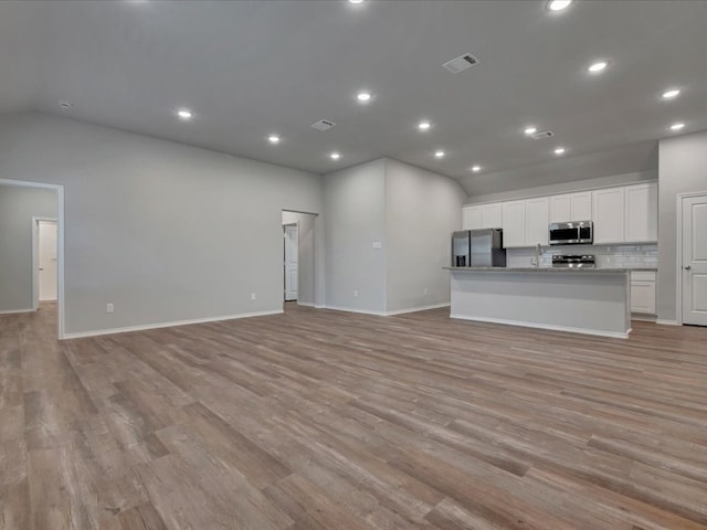 unfurnished living room featuring lofted ceiling, light wood-style flooring, visible vents, and recessed lighting