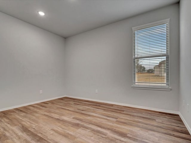 empty room with light wood-style flooring, baseboards, and recessed lighting