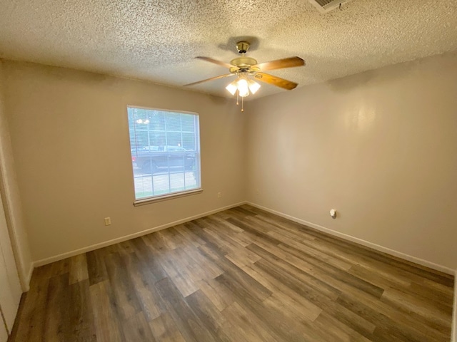 empty room with ceiling fan, dark hardwood / wood-style flooring, and a textured ceiling