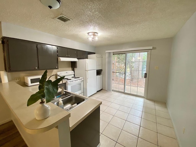 kitchen featuring a textured ceiling, sink, light tile patterned floors, and white appliances