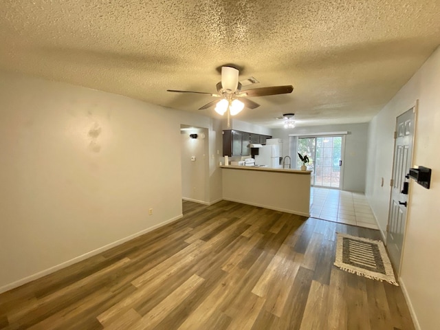 unfurnished living room featuring a textured ceiling, hardwood / wood-style flooring, ceiling fan, and sink