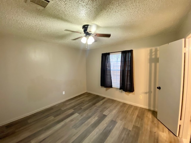 empty room featuring hardwood / wood-style floors, ceiling fan, and a textured ceiling