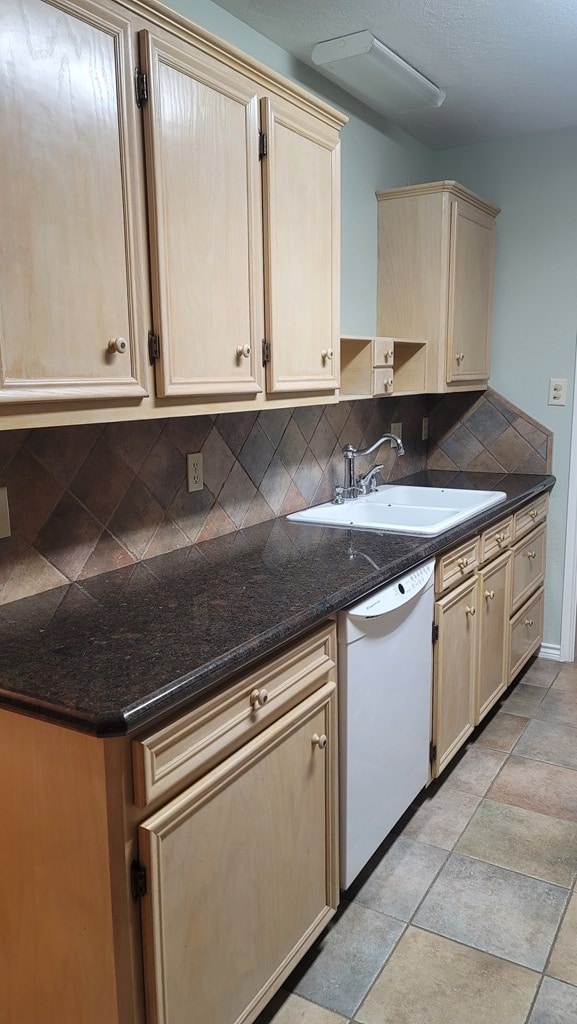 kitchen with backsplash, white dishwasher, and a sink