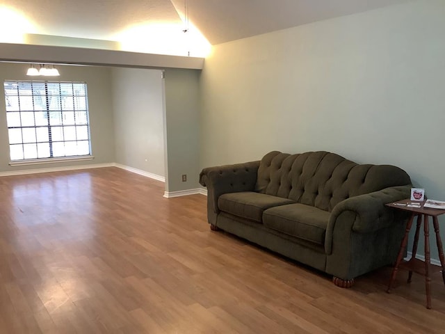 living area featuring vaulted ceiling, baseboards, and wood finished floors