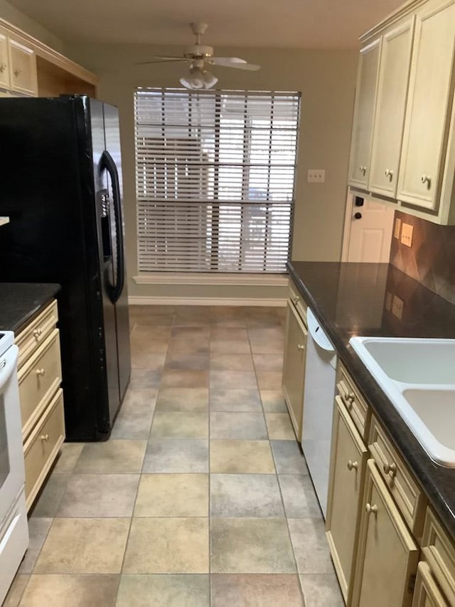 kitchen featuring light tile patterned floors, dark countertops, a ceiling fan, a sink, and white appliances