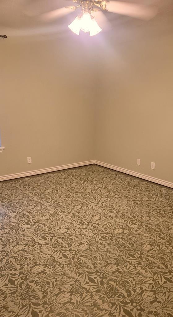 unfurnished room featuring a ceiling fan and baseboards