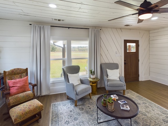 sitting room with wooden walls, dark hardwood / wood-style flooring, ceiling fan, and wooden ceiling