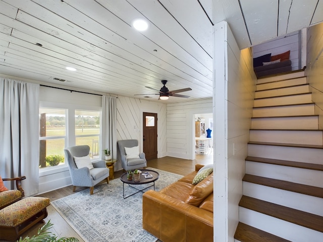 living room featuring hardwood / wood-style floors, ceiling fan, and wooden walls