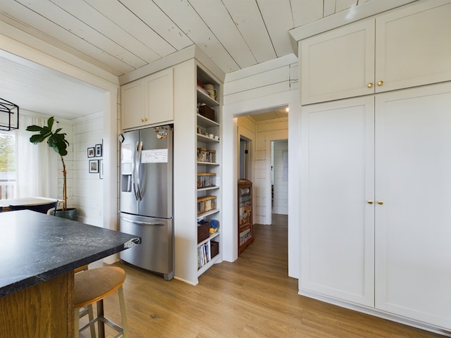 kitchen featuring stainless steel refrigerator with ice dispenser, wood ceiling, light hardwood / wood-style flooring, white cabinets, and wood walls