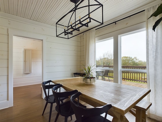 dining room featuring wood walls, dark hardwood / wood-style flooring, and a notable chandelier