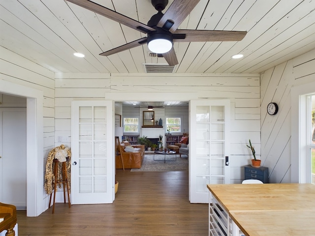 interior space featuring a wealth of natural light, french doors, dark wood-type flooring, and wood walls