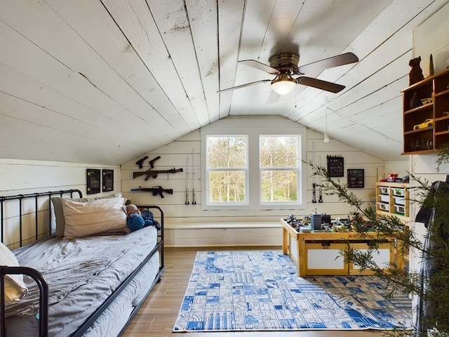 bedroom featuring ceiling fan, lofted ceiling, wooden walls, and light hardwood / wood-style flooring