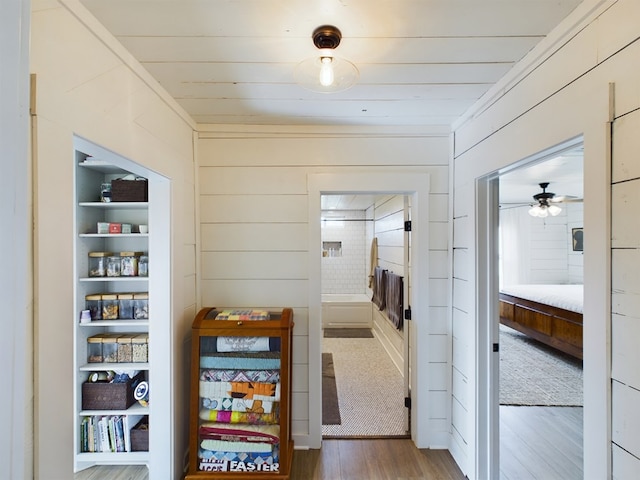 corridor featuring dark hardwood / wood-style floors, wooden walls, and built in shelves