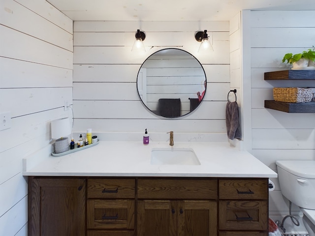 bathroom featuring wood walls, vanity, and toilet