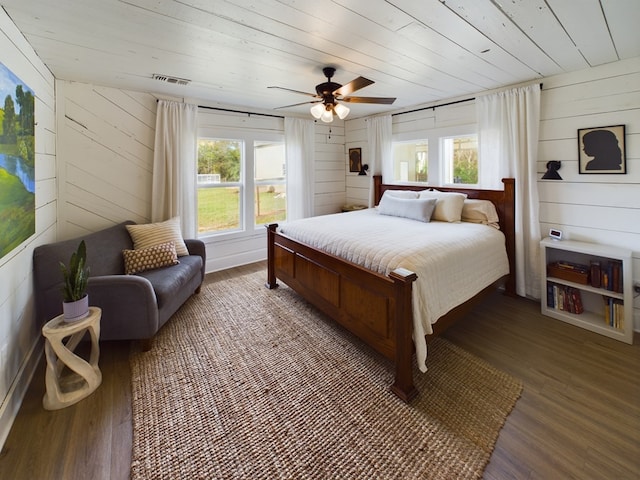 bedroom featuring ceiling fan, dark wood-type flooring, and wood walls