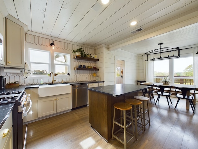 kitchen with sink, a kitchen island, a healthy amount of sunlight, and appliances with stainless steel finishes