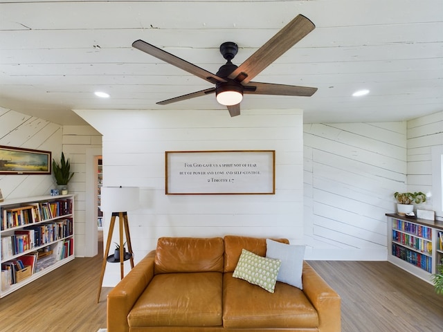 living room with wood-type flooring, ceiling fan, and wooden walls