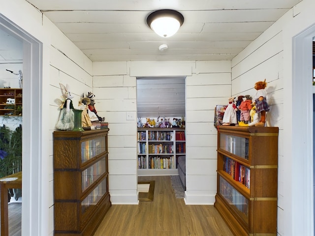 hall with hardwood / wood-style floors and wood walls