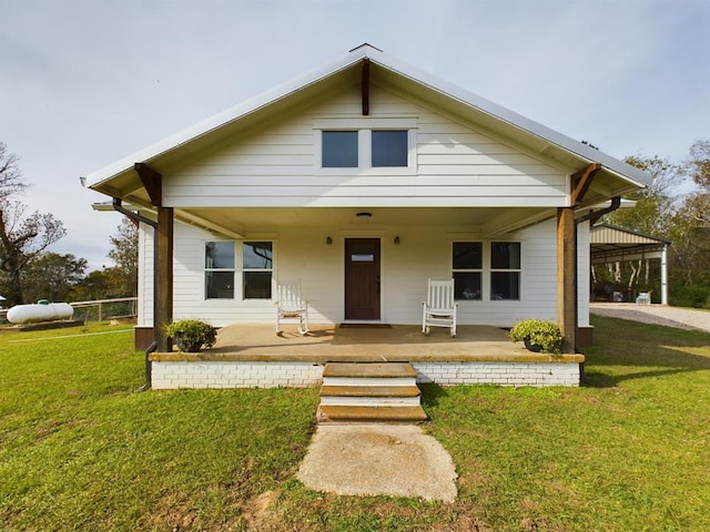 rear view of house featuring covered porch and a lawn