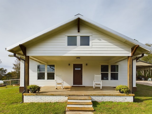 rear view of property featuring a yard and a porch