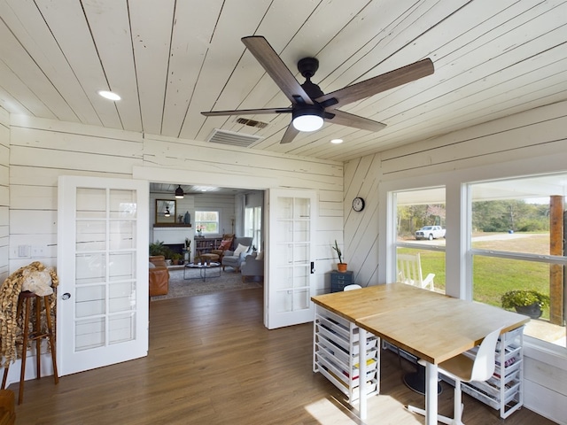 dining area featuring wood walls, dark wood-type flooring, and a healthy amount of sunlight