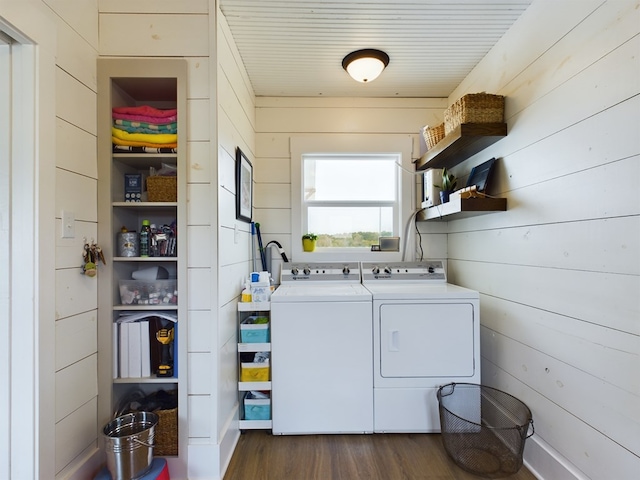 laundry room with washer and clothes dryer, wood walls, and dark hardwood / wood-style flooring