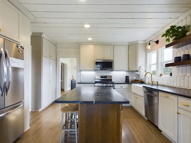 kitchen with decorative backsplash, appliances with stainless steel finishes, a center island, and dark hardwood / wood-style flooring