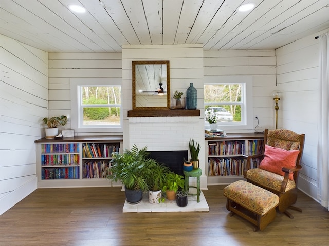 sitting room with wooden ceiling, a wealth of natural light, dark wood-type flooring, and wood walls