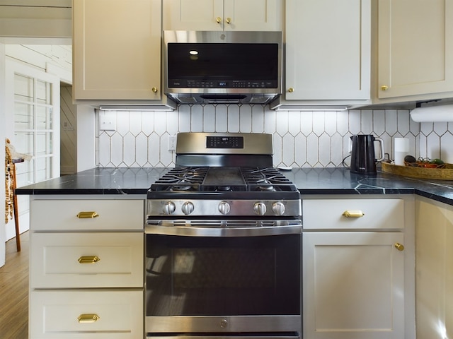 kitchen with appliances with stainless steel finishes, tasteful backsplash, and dark stone counters